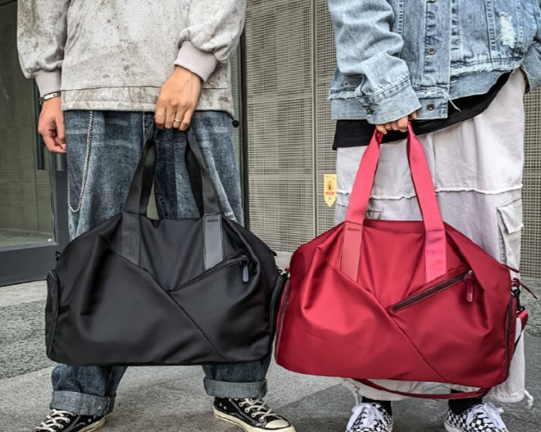 Two people holding a black and a red bag respectively, standing outdoors.