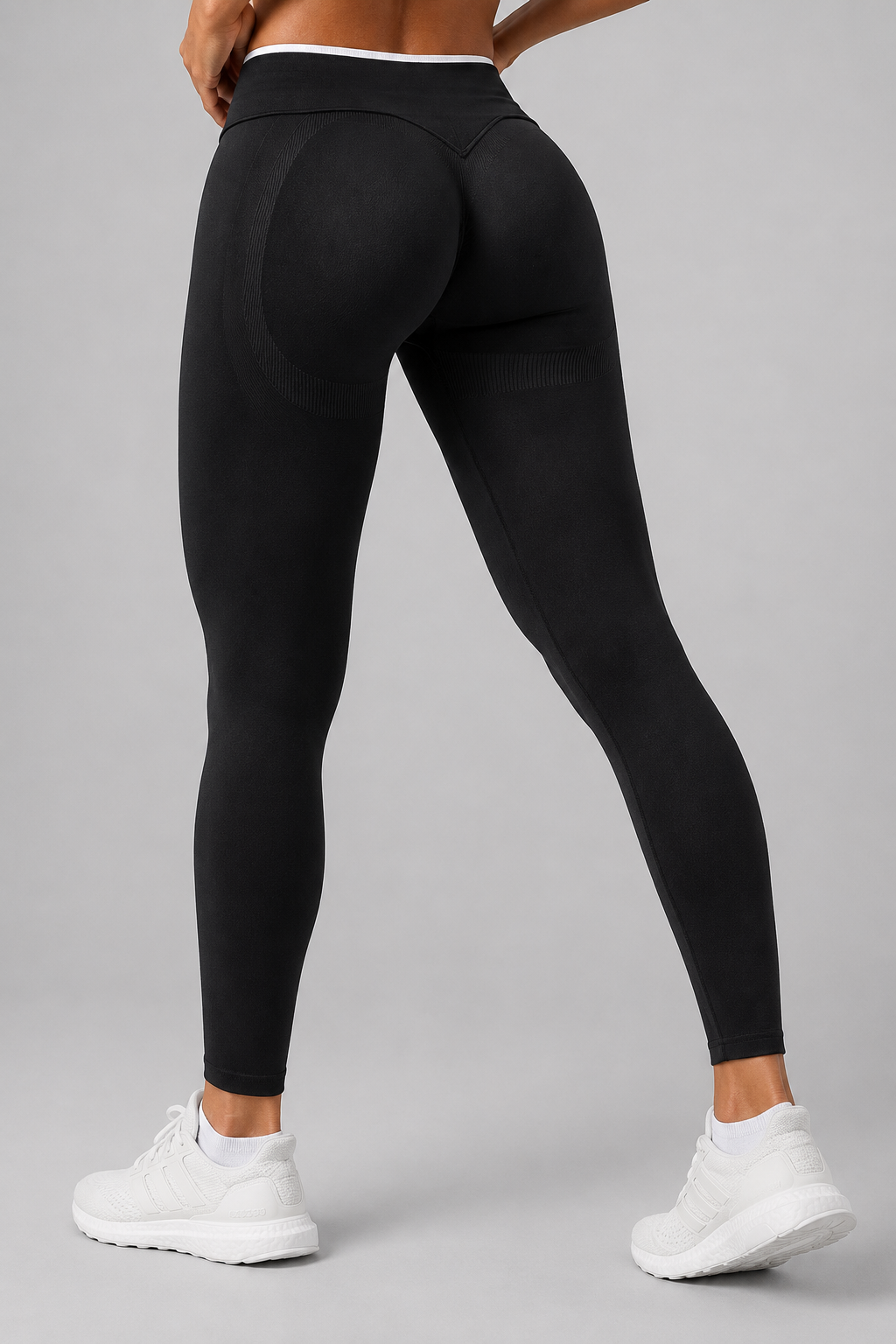 Person wearing black leggings and white sneakers on a gray background