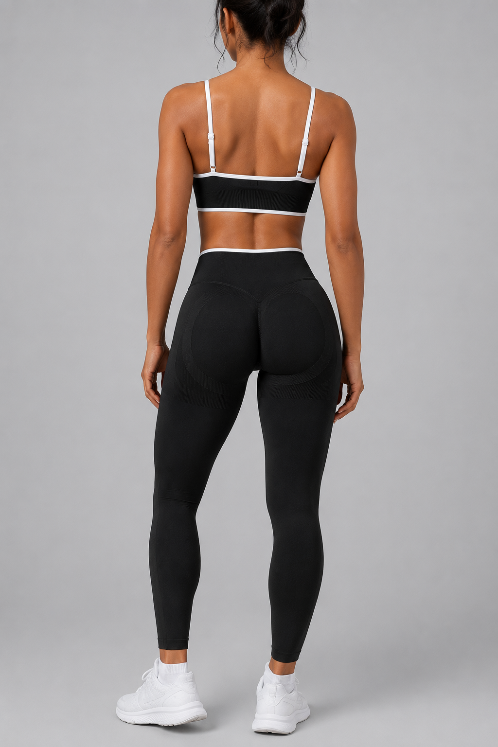 Person wearing a black sports bra and leggings set on a gray background