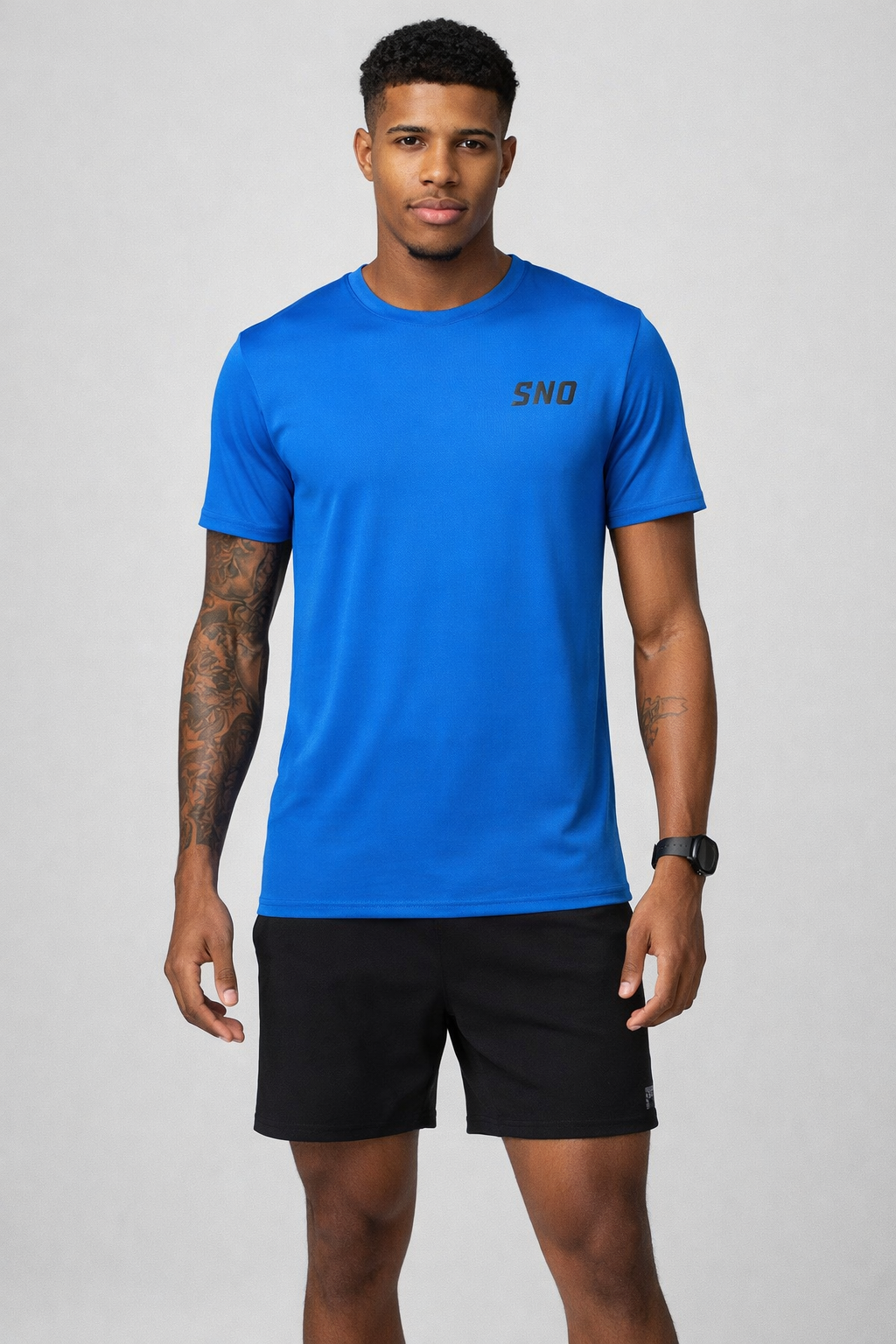 Man wearing a blue t-shirt with 'SNO' logo and black shorts on a gray background