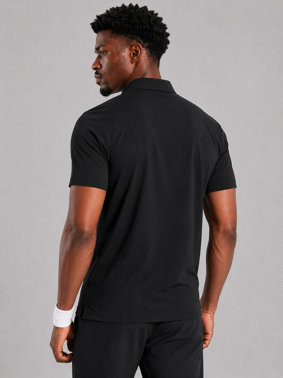 Man wearing a black polo shirt and black pants on a gray background