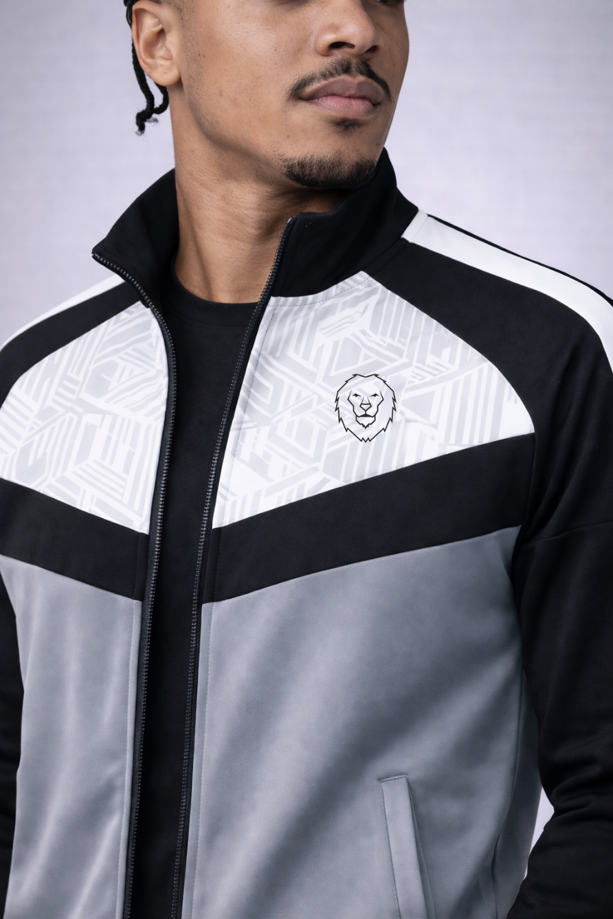 Person wearing a black, white, and gray jacket with a logo on a light gray background. Men's Tracksuit - SNO