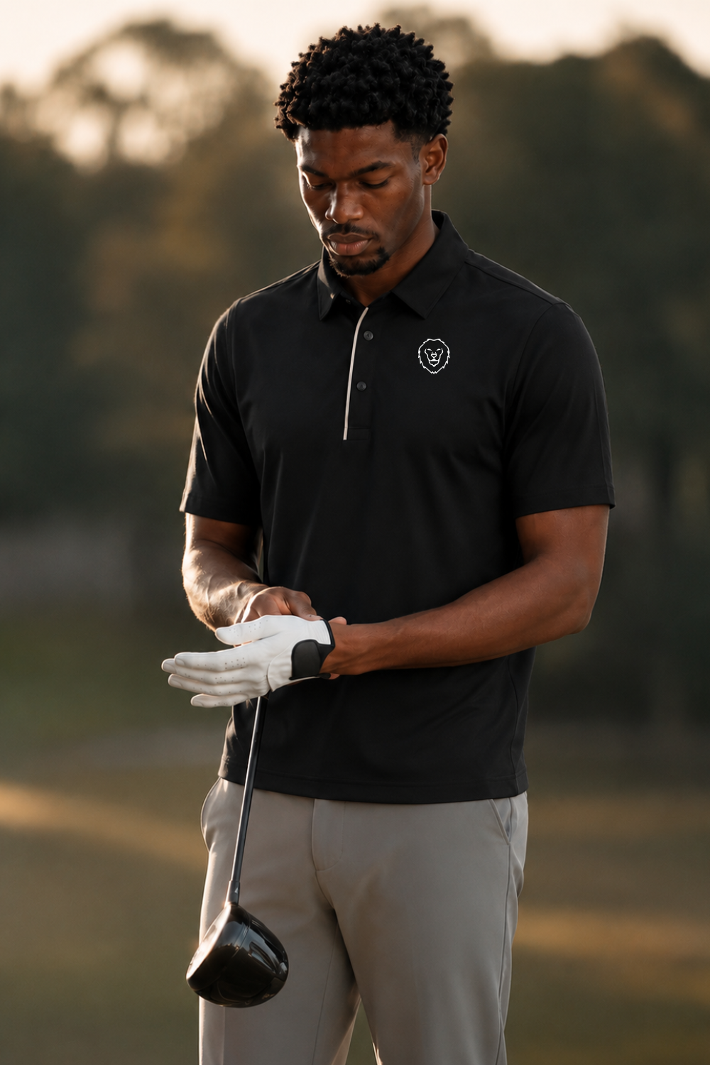 Man wearing a black polo shirt and black pants on a golf course background