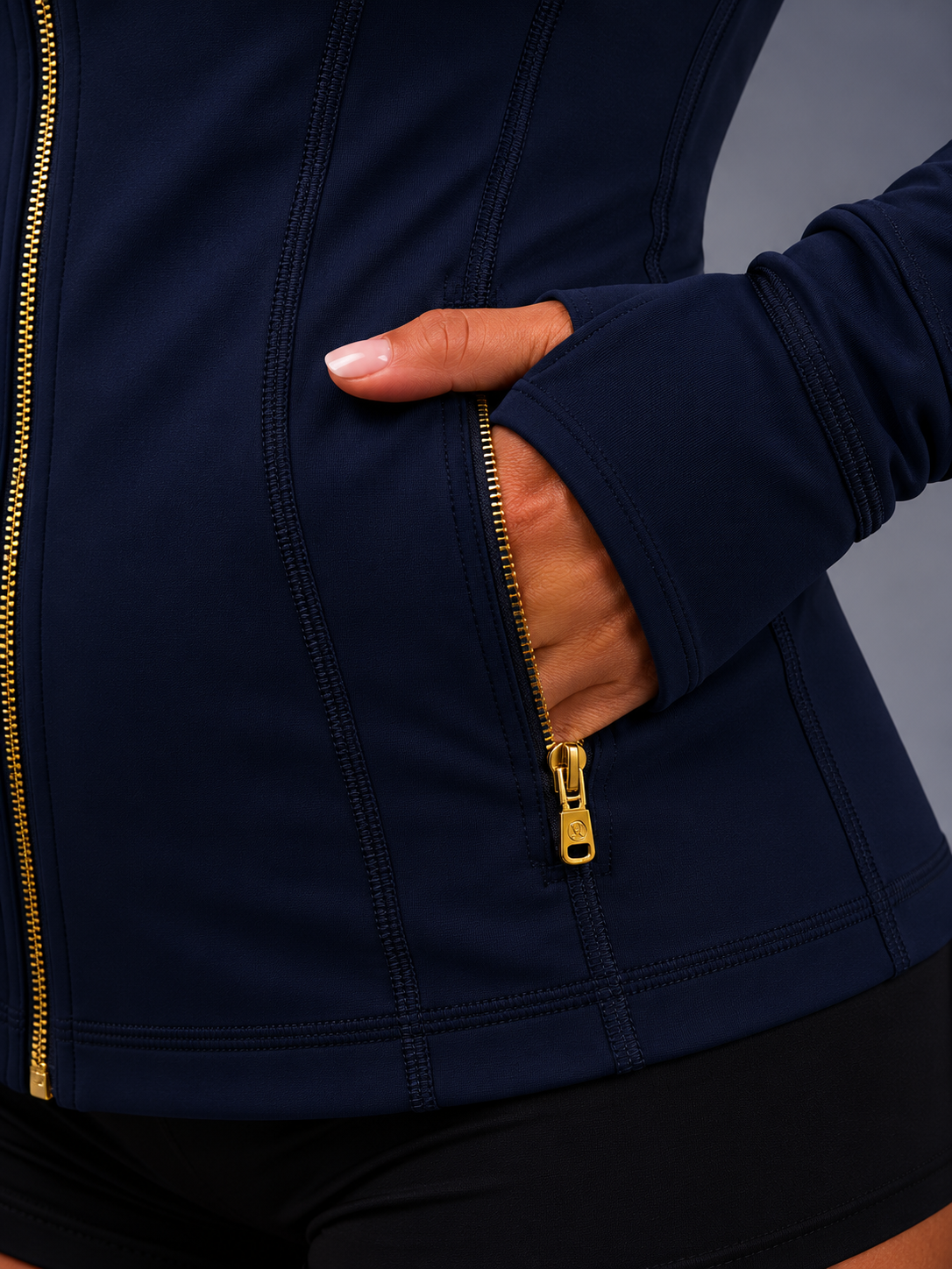 Navy blue jacket with gold zipper being unzipped on a gray background