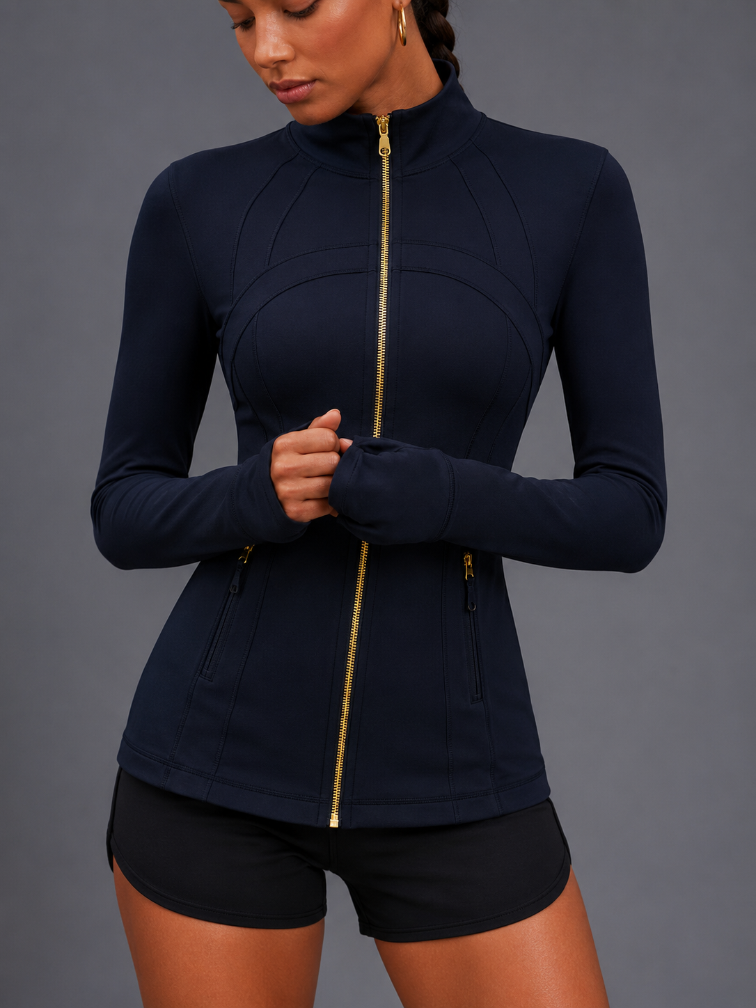 Person wearing a navy blue athletic jacket with a gold zipper on a gray background
