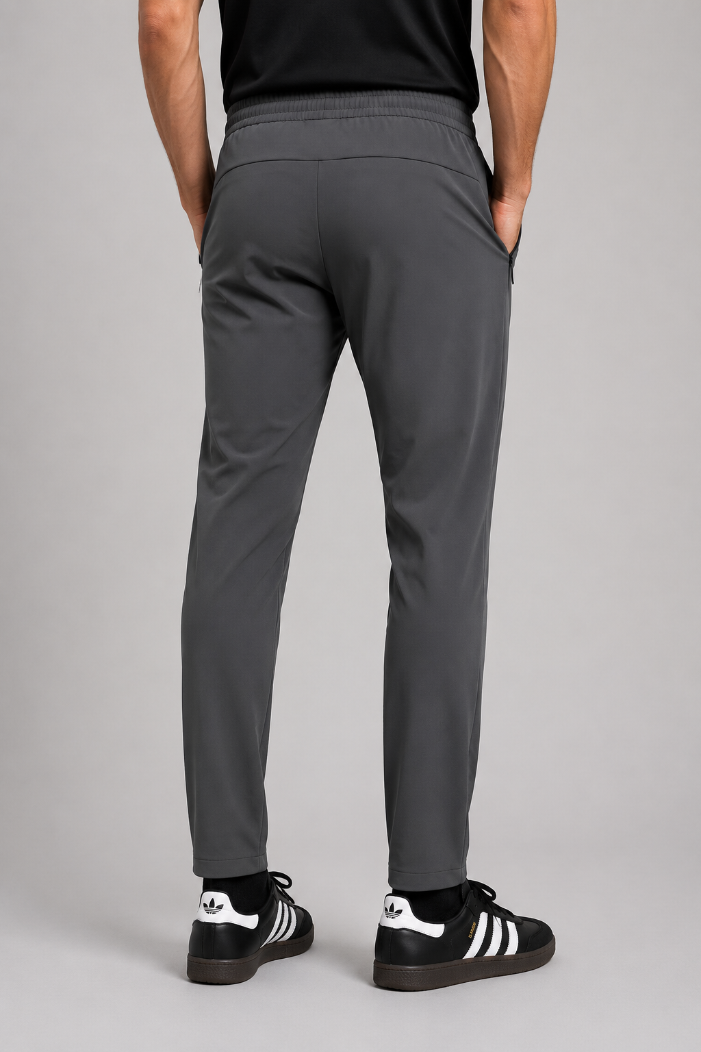 Person wearing gray pants and black Adidas shoes on a gray background