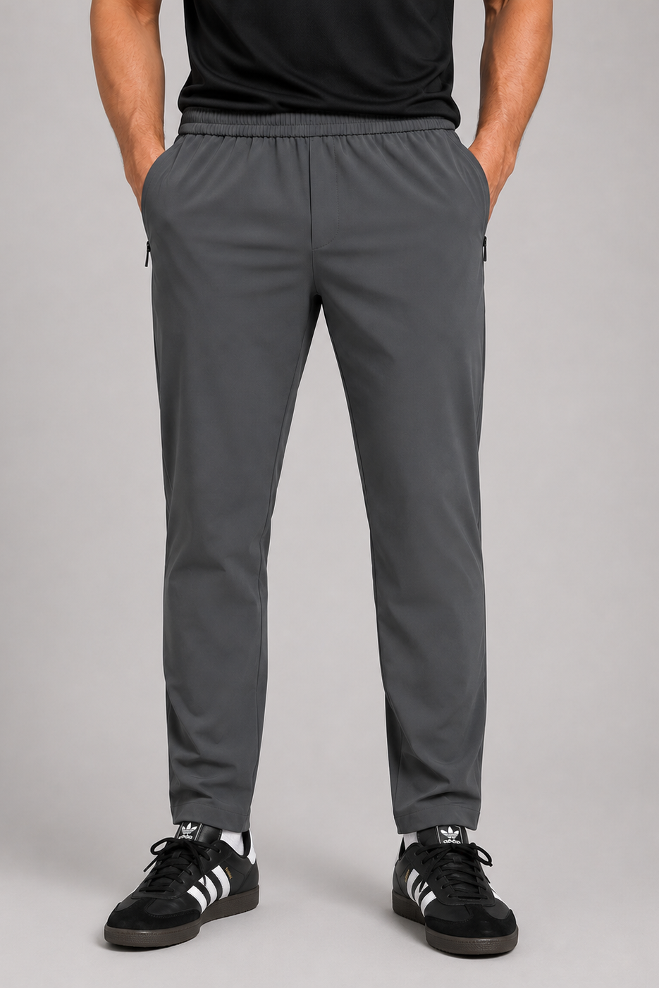 Person wearing gray pants and black Adidas shoes on a gray background