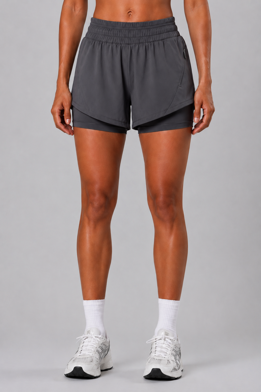 Person wearing gray athletic shorts on a gray background
