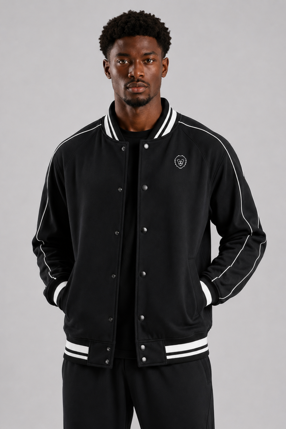 Man wearing a black varsity jacket with white accents on a gray background
