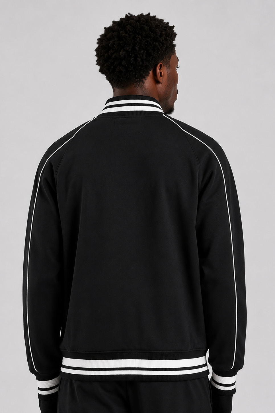 Person wearing a black track jacket with white stripes on a gray background