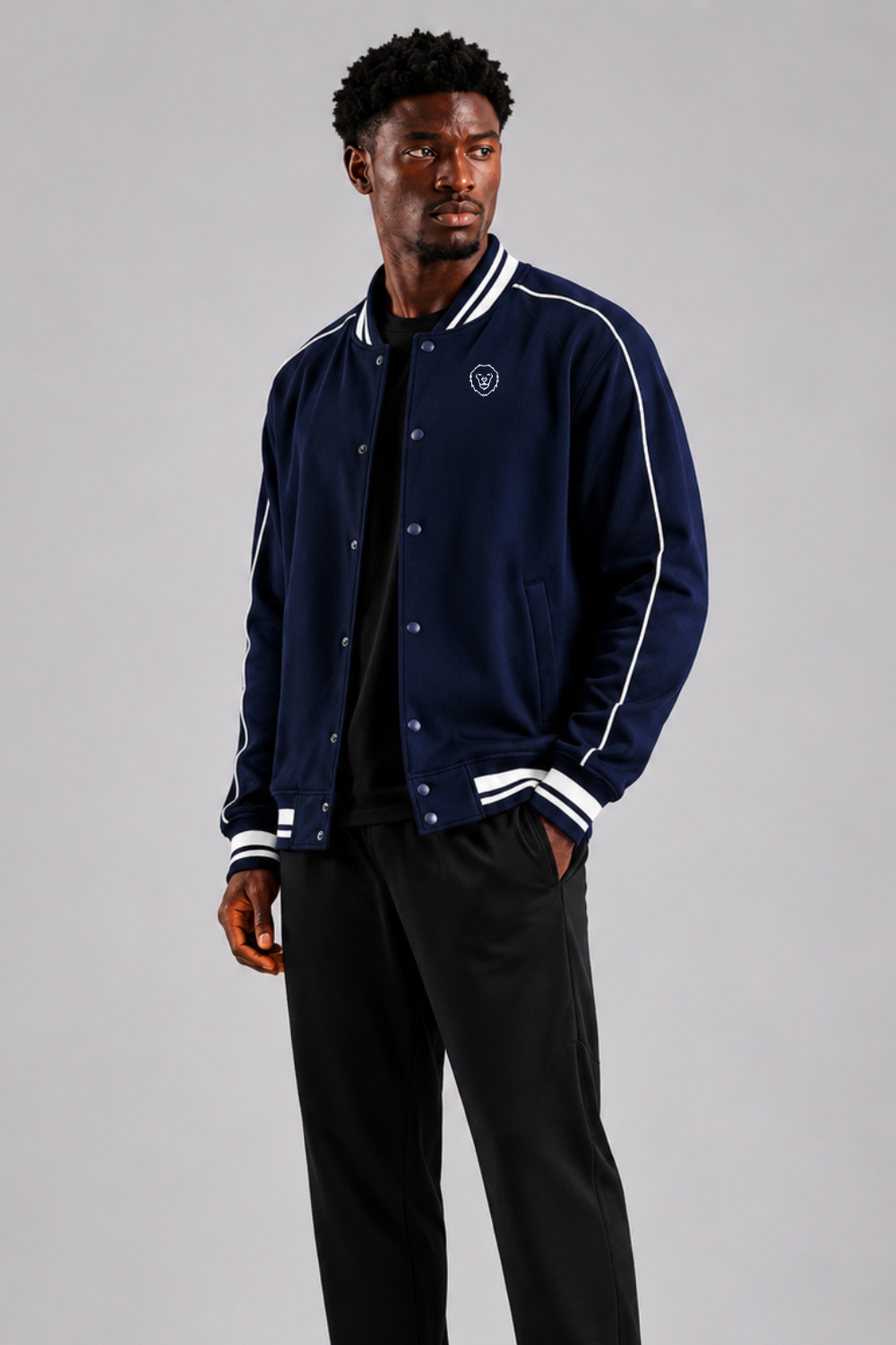 Man wearing a navy blue varsity jacket with white accents on a gray background