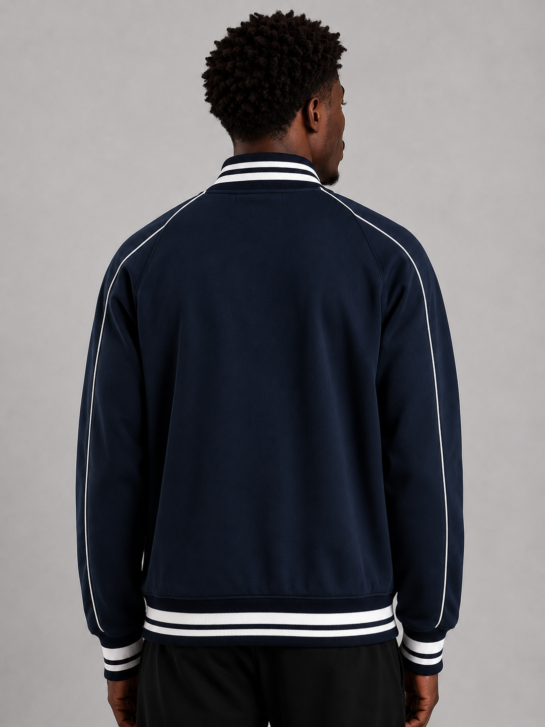 Person wearing a navy blue tracksuit with white stripes on a gray background