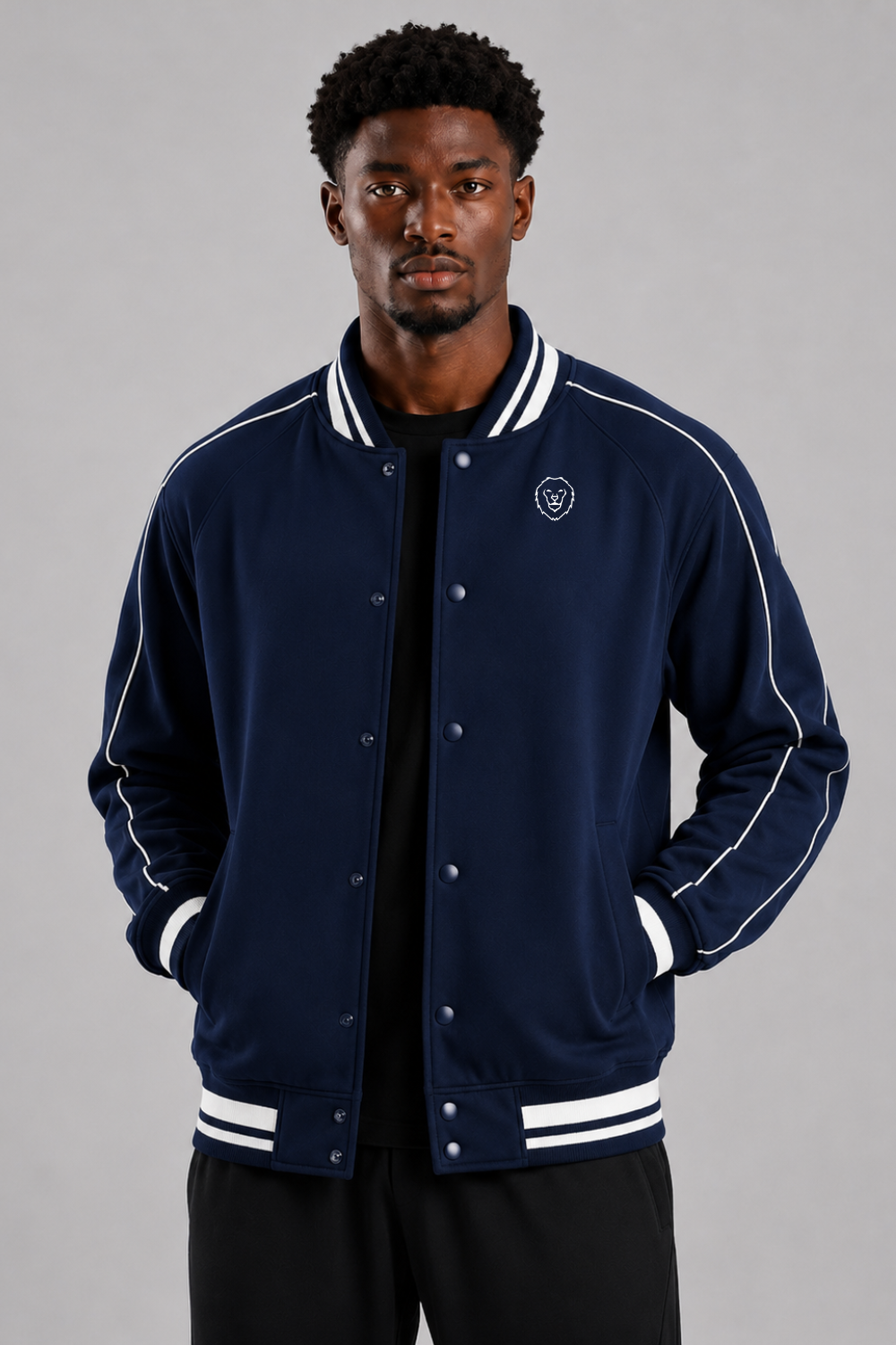 Man wearing a navy blue varsity jacket with white accents on a gray background