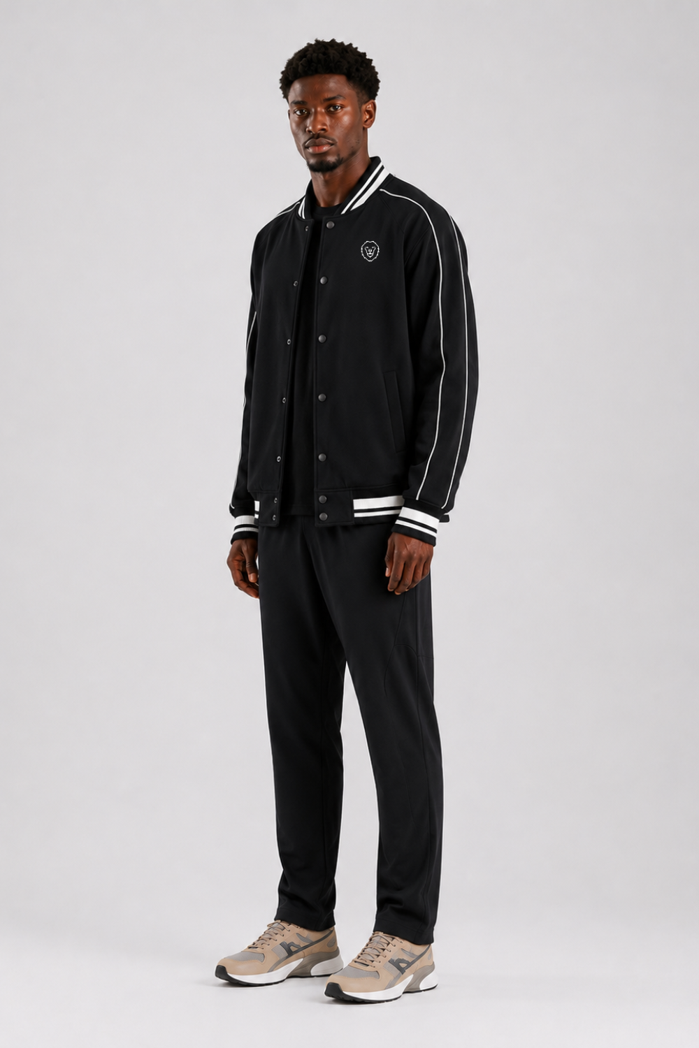 Man wearing a black varsity jacket with white stripes on a white background