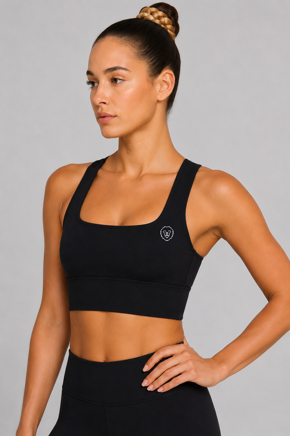Woman wearing a black sports bra with a logo on a gray background