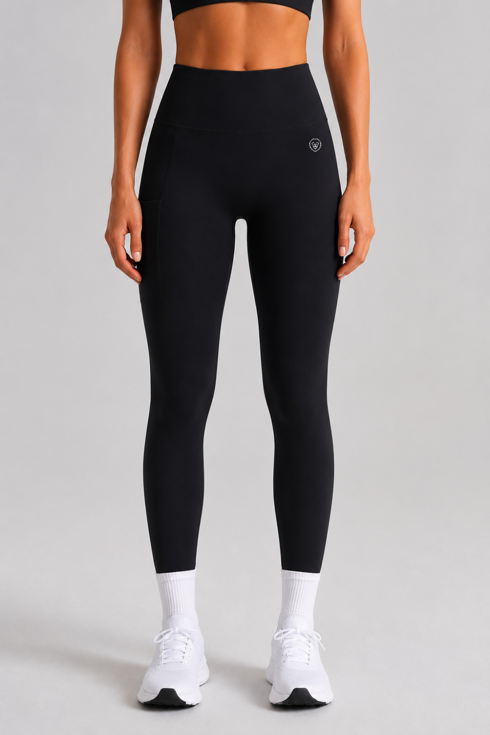 Person wearing black leggings and white sneakers on a gray background