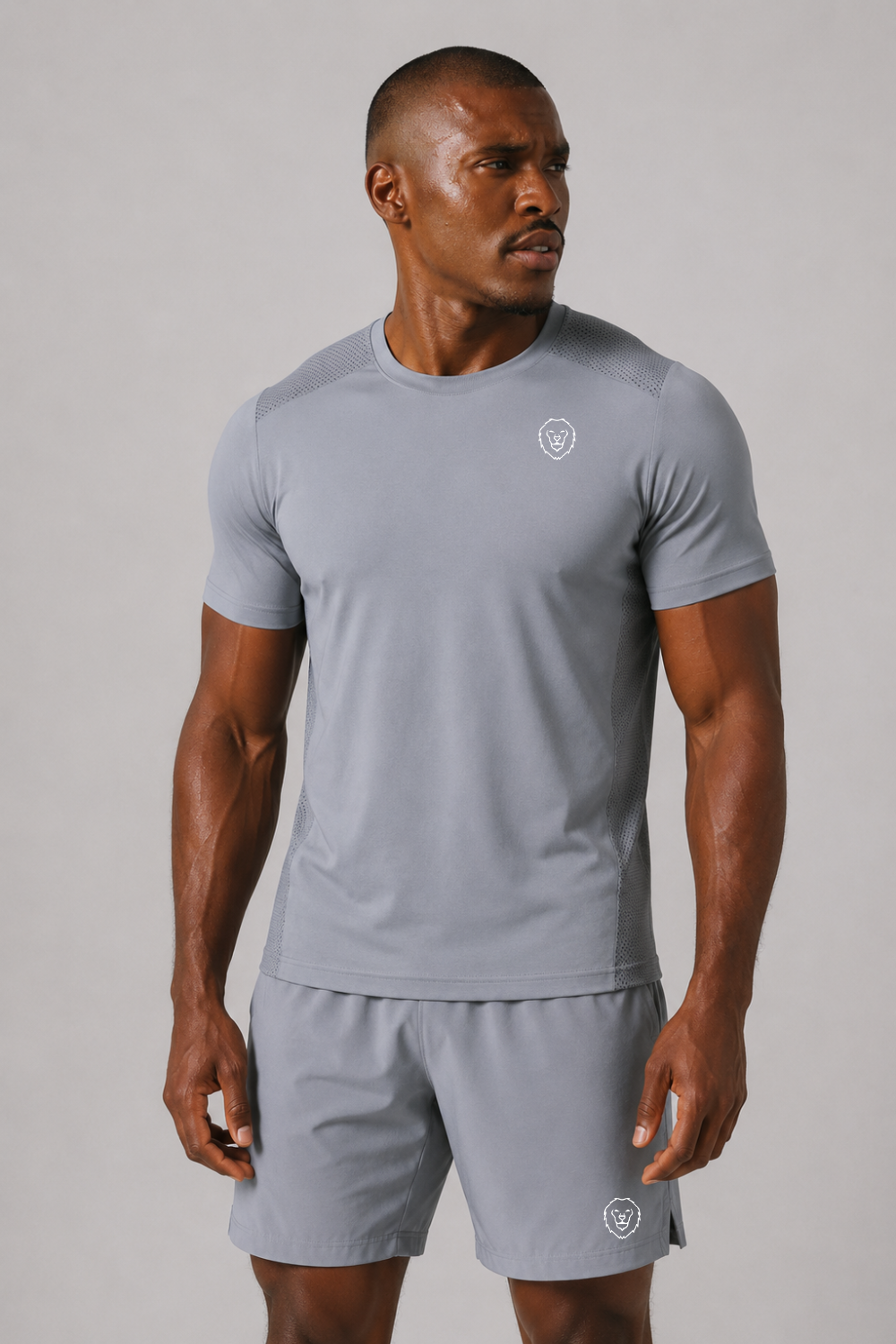 Man wearing a gray athletic outfit with a logo on a plain background
