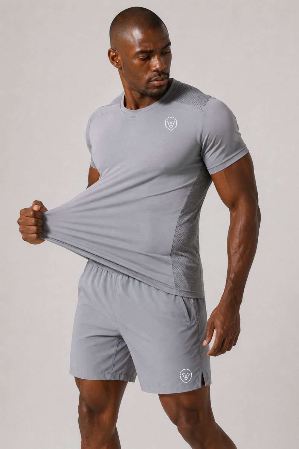 Man wearing a gray athletic outfit with a logo on a plain background