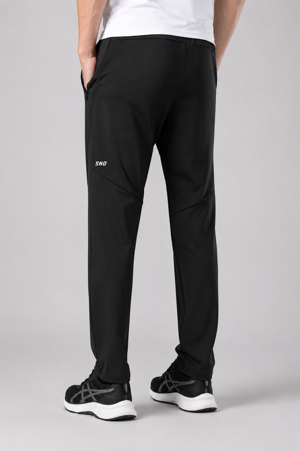 Person wearing black pants with a brand logo on a gray background