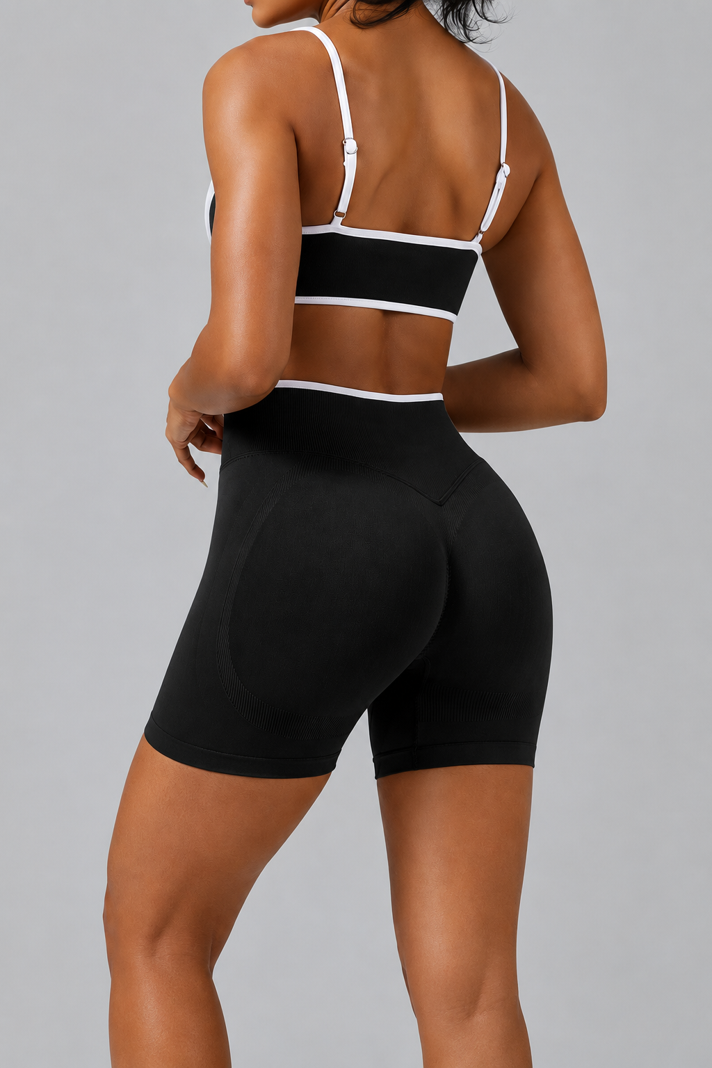 Person wearing a black sports bra and shorts on a gray background