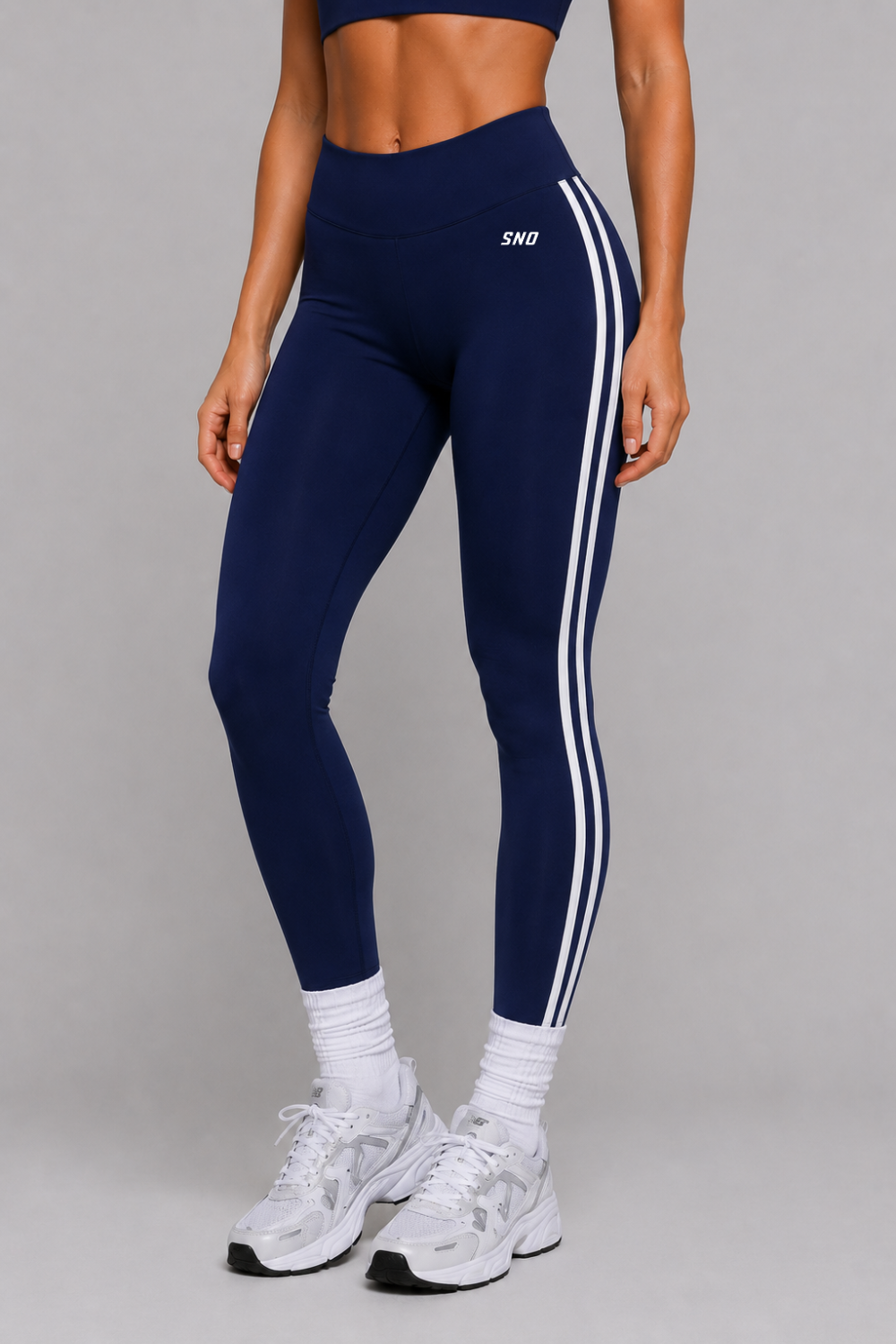 Navy leggings with white stripes worn by a person on a gray background