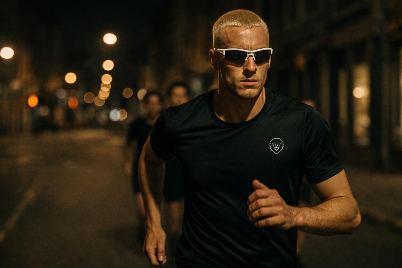 Man running on a street at night wearing sunglasses and a black t-shirt with a logo.