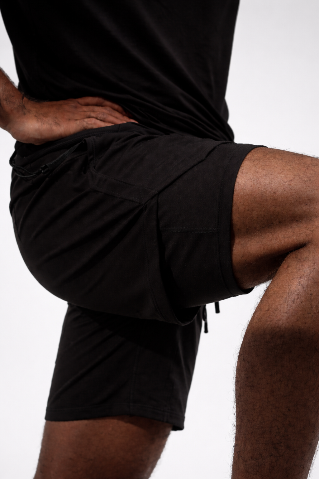 Person wearing black athletic shorts on a white background